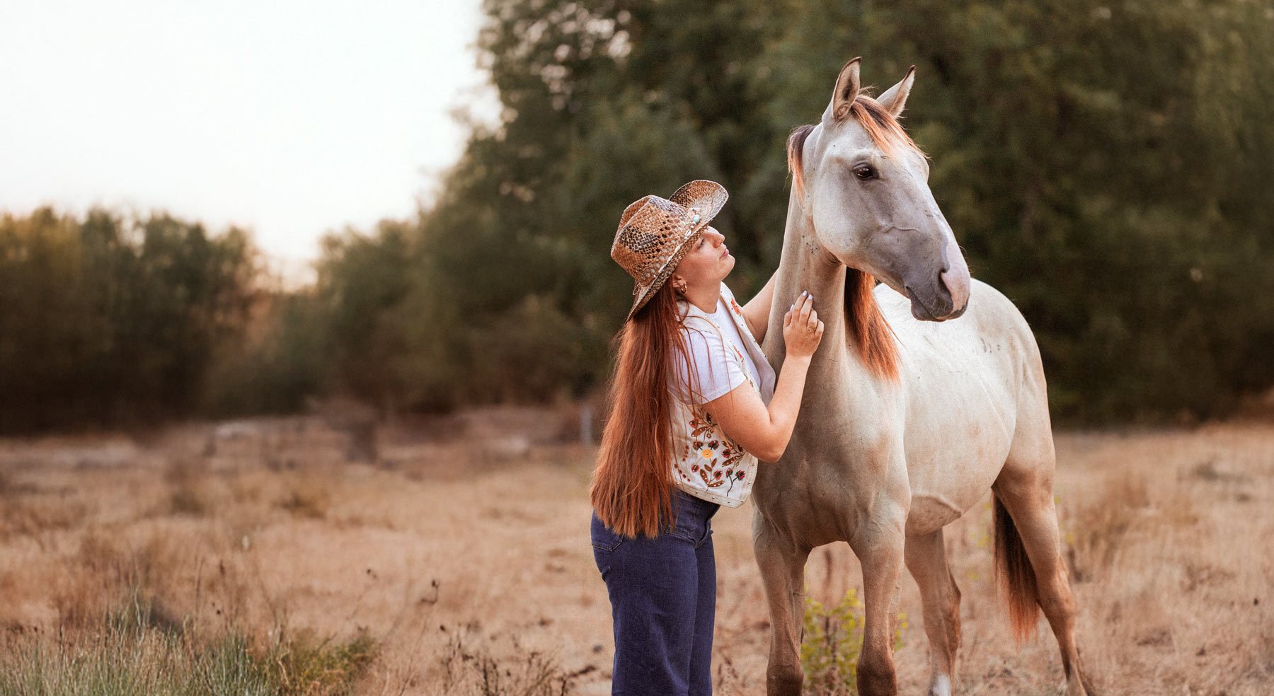 Cavalière auprès de son cheval au coucher du soleil